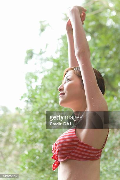 woman stretching arms out in woods, in a bathing suit, side view, japan - thermal suit stockfoto's en -beelden