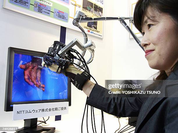 Japan's telecom giant NTT's subsidiary NTT Comware employee Mayumi Tamura displays the 3D hand shaking system, which enables user to shake hands with...