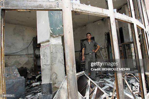 An Iranian employee of a petrol station which was burnt last night by angry demonstrators smokes a cigarette inside the damaged office of the station...