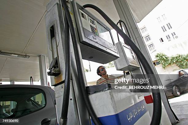 An Iranian man looks at his petrol quota before pumping fuel at a petrol station north of Tehran, 27 June 2007. Angry demonstrators torched petrol...