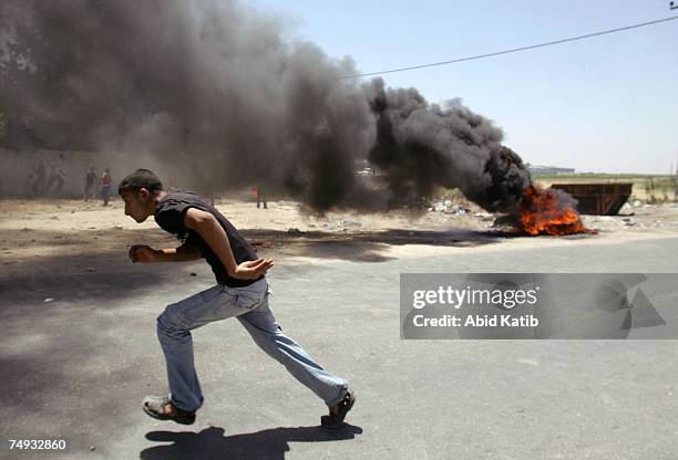 Palestinian bystander runs next to burning tires during clashes on June 27, 2007 in Gaza City, Gaza Strip. Israeli forces killed at least 13...