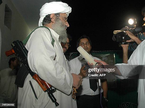 Abdul Rashid Ghazi , deputy head of the Red Mosque carries a gun as he speaks with media at an Islamic seminary in Islamabad, 27 June 2007. A radical...