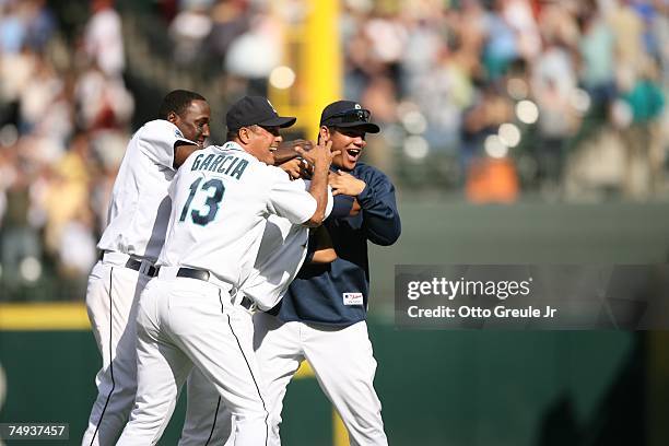 Jose Lopez of the Seattle Mariners is mobbed by Yuniesky Betancourt, third base coach Carlos Garcia and pitcher Felix Hernandez after hitting the...