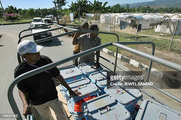 Convoy carrying ballot boxes pass by a refugee camp to the airport in Dili, 28 June 2007, two days ahead of the parliament election. Political...