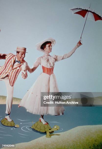 American actor Dick Van Dyke as Bert/Mr. Dawes, Sr. And English actress Julie Andrews in the title role, cross a river using turtles as...