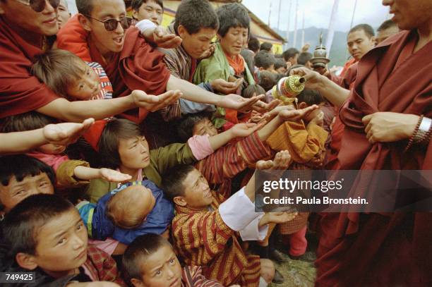 In the village of Jakar during the Supreme Prayer festival, known in Bhutanese as "Melam Chenpo," crowds gather with hands outstretched to get a drop...