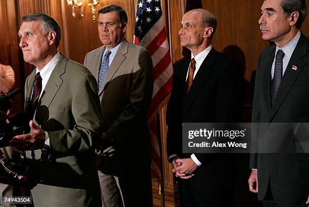 Sen. Jon Kyl pauses as Sen. Mel Martinez , Homeland Security Secretary Michael Chertoff, and Commerce Secretary Carlos Gutierrez look on during a...