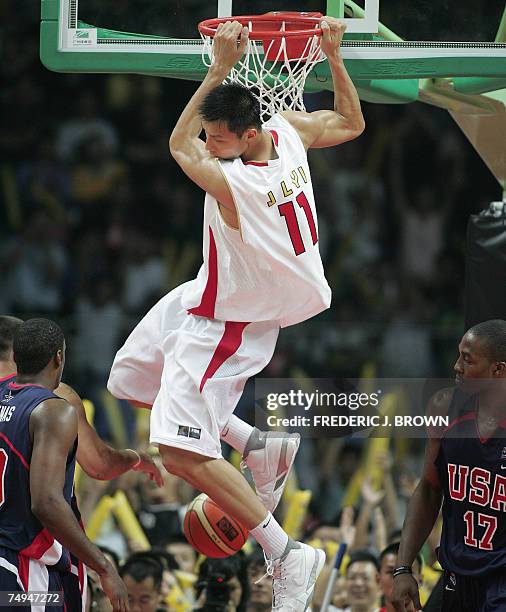 China's Yi Jianlian hangs onto the rim after slam dunking past USA's Brad Miller , Gilbert Arenas and Dwight Howard , 07 August 2006 at the China...