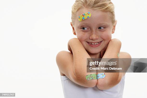 girl (7-9) with plasters on head and arms, smiling - penso rápido imagens e fotografias de stock