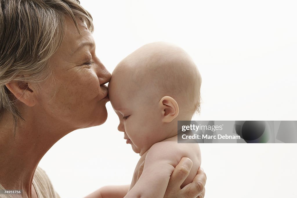 Grandmother kissing baby grandson (0-3 months)