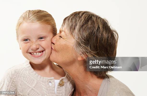 grandmother kissing granddaughter (7-9), smiling - grootmoeder witte achtergrond stockfoto's en -beelden
