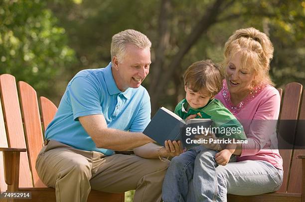 grandparents reading to their grandson - adirondack chair closeup stock pictures, royalty-free photos & images