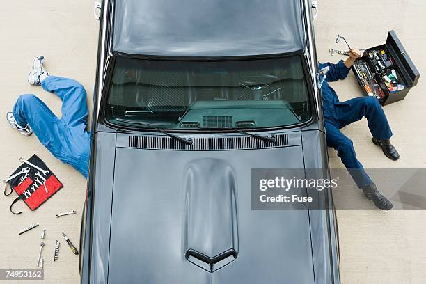 two mechanics repairing car - laying on car hood stock pictures, royalty-free photos & images