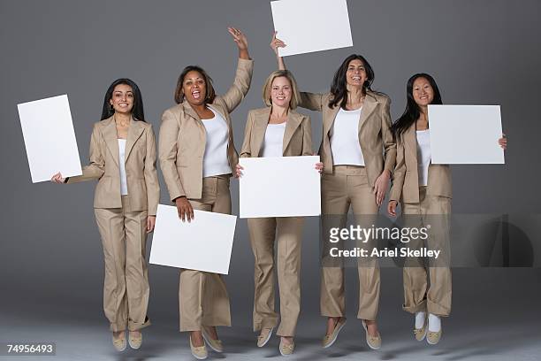 multi-ethnic businesswoman jumping and holding signs - office holding sign stockfoto's en -beelden