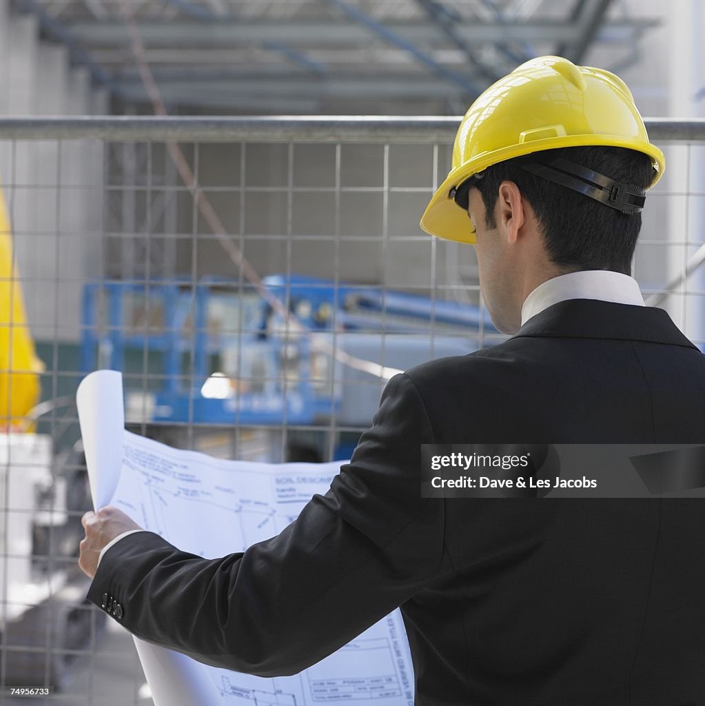 Businessman in hardhat looking at blueprints