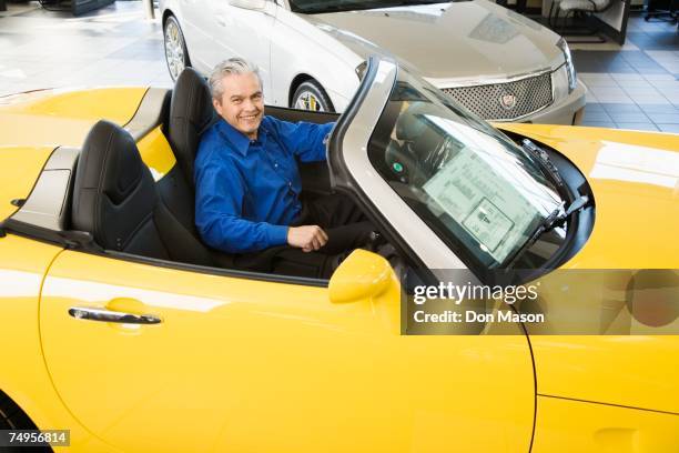 hispanic car salesman sitting in new car - medelålderskris bildbanksfoton och bilder