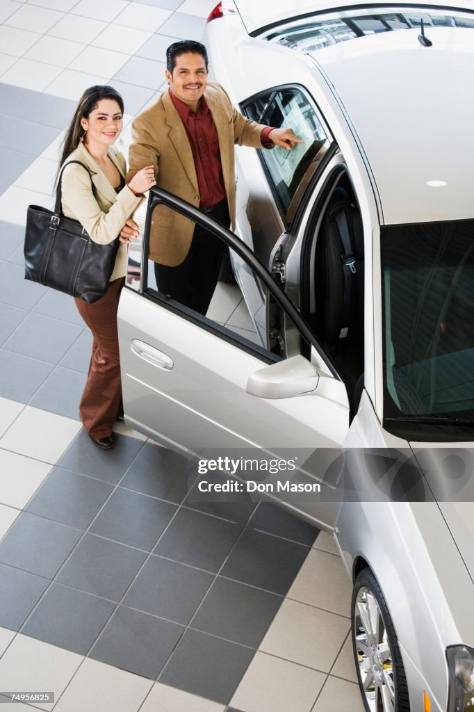 Hispanic couple looking at new car