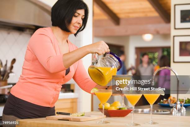 middle-aged hispanic woman pouring cocktails - 4 cocktails stockfoto's en -beelden