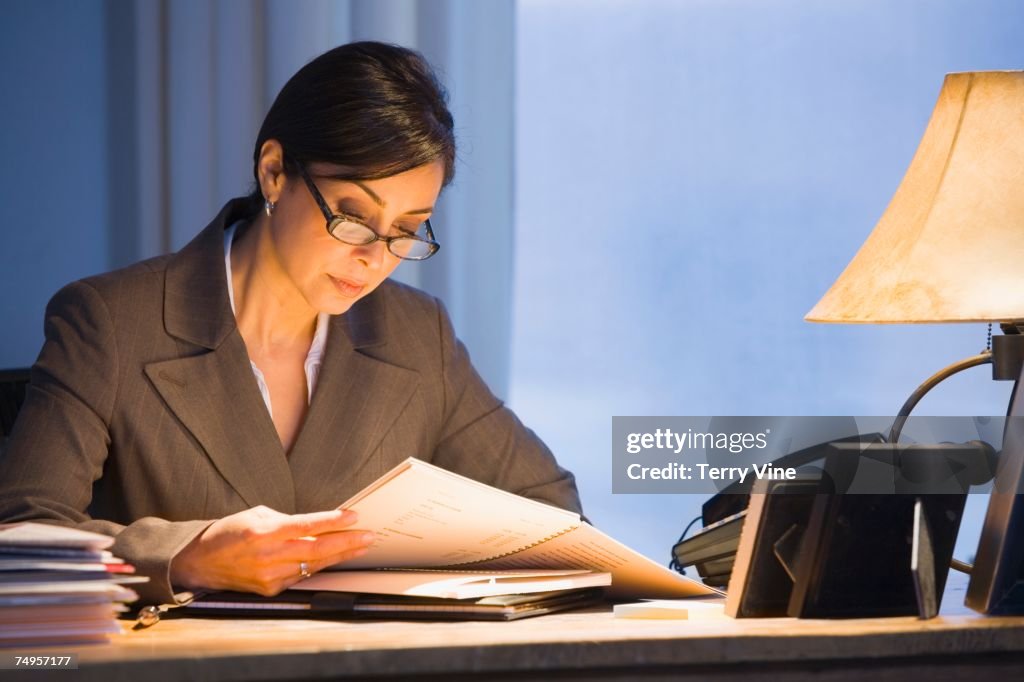 Hispanic businesswoman reading paperwork