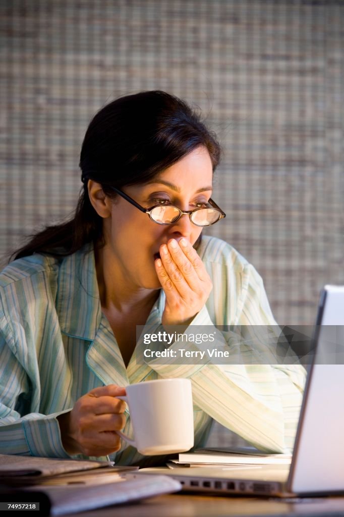 Hispanic businesswoman working in pajamas