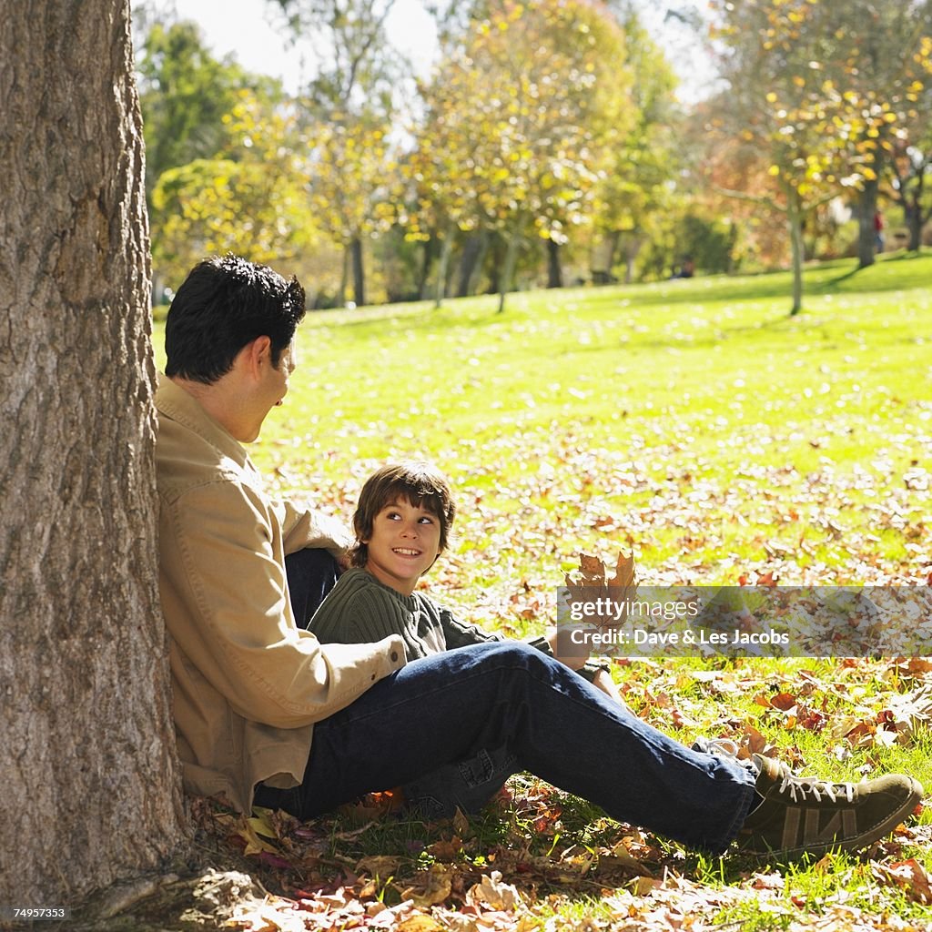 Mixed Race father and son sitting in park