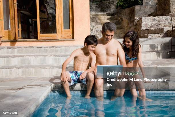 father and children using laptop in swimming pool - hot boy body stock-fotos und bilder