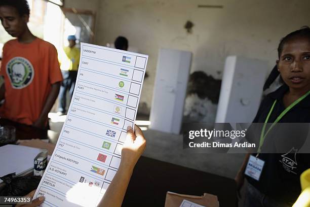 An East Timorese receives her ballot form from an election officer in a polling station, June 30, 2007 in Dili, East Timor. East Timor goes to the...