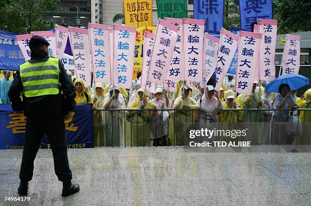 Policeman stands guard as Falun Gong practioners hold a protest near a hotel where Chinese President Hu Jintao is staying in Hong Kong, 30 June 2007....