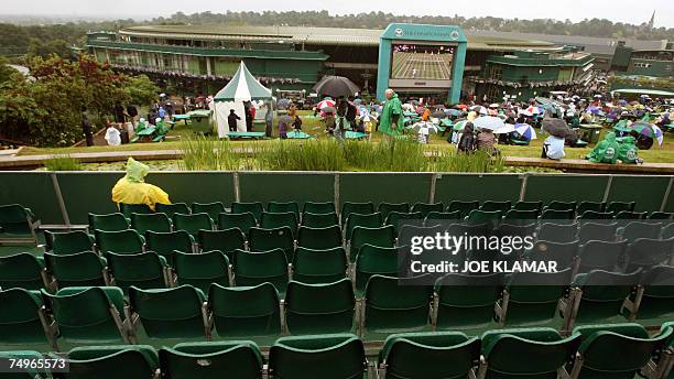 London, UNITED KINGDOM: A Tennis fan sits on "Henman Hill" as rain delays the start of the sixth day of the 2007 Wimbledon championships in...