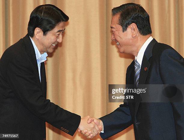 Japanese Prime Minister and ruling Liberal Democratic Party leader Shinzo Abe shakes hands with main opposition Democratic Party of Japan leader...