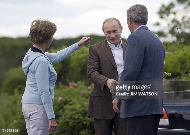 First Lady Laura Bush reaches out to fix Russian President Vladamir Putin's collar as he shakes hands with US President George W. Bush as he arrives...