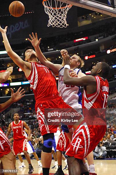 Yao Ming of the Houston Rockets and Chris Kaman of the Los Angeles Clippers, center, battle for ball as Kirk Snyder of the Rockets watches in NBA...