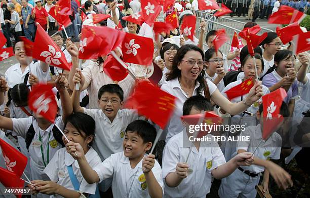 School children and teachers wave Chinese and Hong Kong flags after the flag raising ceremonies outside the Hong Kong Convention and Exhibition...