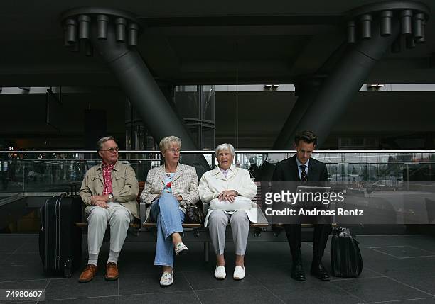 Business man uses his laptop as pensioners rest on a bench at Berlin Central Station on July 2, 2007 in Berlin, Germany. Workers of German railway...