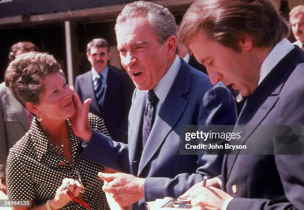 Former American President Richard Milhous Nixon pats the cheek of a woman while British newscaster Sir David Frost signs an autograph after an...