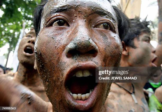 Jakarta, Java, INDONESIA: Environmental activists covered with mud shout slogans during a demonstration against Lapindo Brantas, a company linked to...