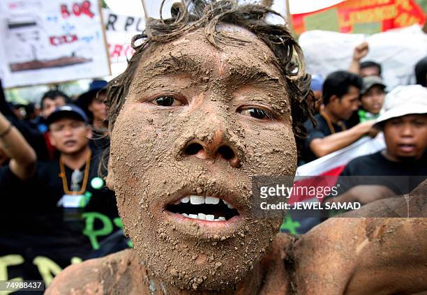 Jakarta, Java, INDONESIA: An environmental activist covered with mud shouts slogans along with others during a demonstration against Lapindo Brantas,...