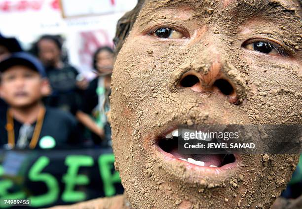 Jakarta, Java, INDONESIA: An environmental activist covered with mud shouts slogans along with others during a demonstration against Lapindo Brantas,...