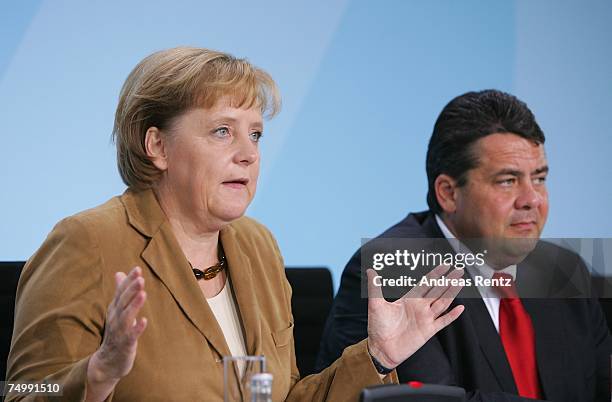 German Chancellor Angela Merkel speaks as Environment Minister Sigmar Gabriel looks on during a press conference after the third energy summit at the...