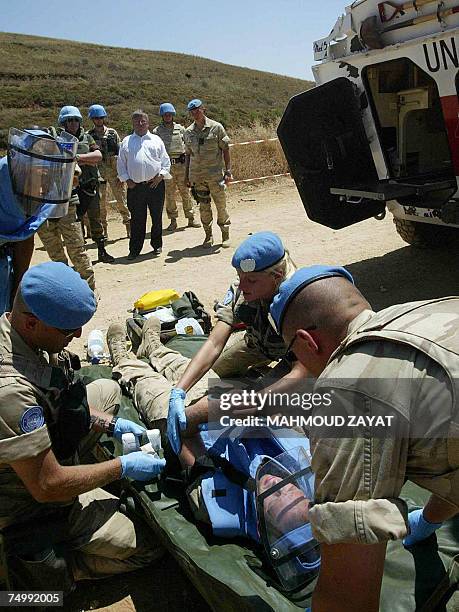 Belgian Defence Minister Andre Flahaut looks at Belgian soldiers treating a mock wounded soldier during a drill near their camp in the southern...