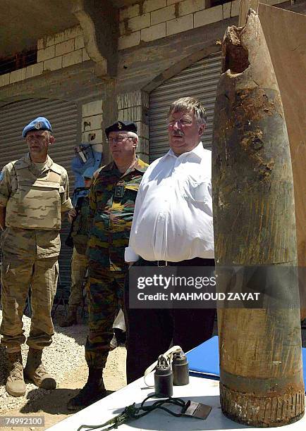 Belgian Defence Minister Andre Flahaut stands near an unexploded shell as he looks at Belgian soldiers treating a mock wounded soldier during a drill...
