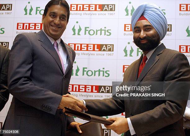 Director of Ansal Properties & Infrastructure Ltd. Pranav Ansal exchanges documents with Managing Director of Fortis Group Shivinder Singh in New...