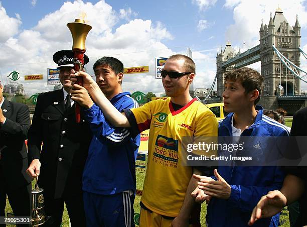 Xu Chuang of China and Jonathan Riggans of Great Britain hold the torch during the DHL-Special Olympics Torch run 'Flame of Hope', on July 4, 2007 in...