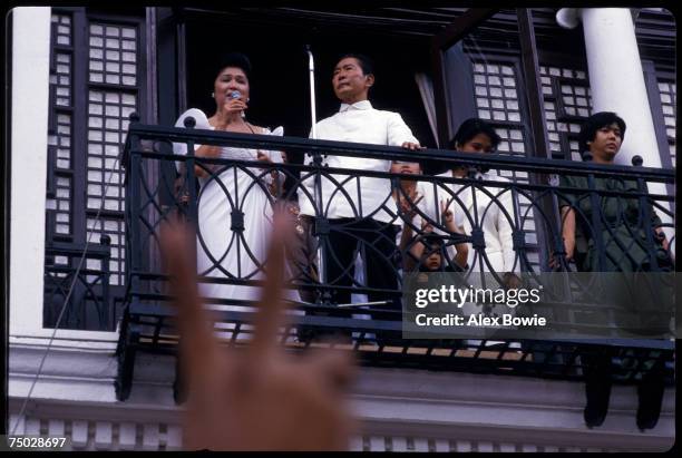 Philippine President Ferdinand Marcos stands by as his wife Imelda sings to supporters from a balcony of the Malacanang Palace in Manila after...