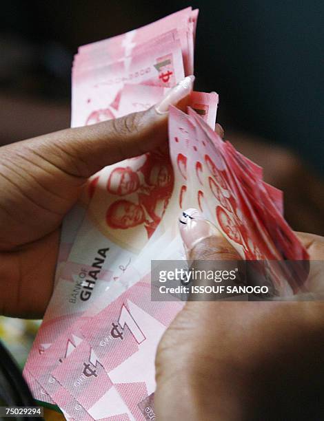 Woman holds 03 July 2007 in Accra a wad of new currency, the new cedi, that Ghana put in circulation that day, although the old money will still be...
