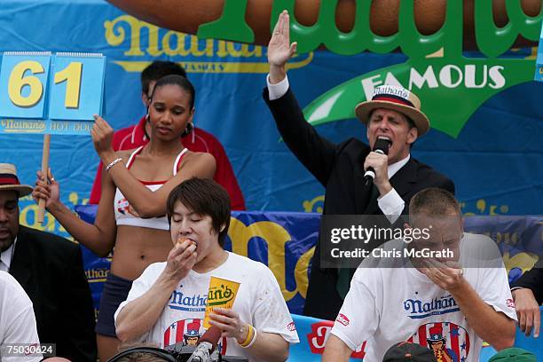 Takeru Kobayashi of Japan and Joey Chestnut of San Jose stuff hotdogs in their mouths in the closing minutes of the annual hot dog eating contest at...