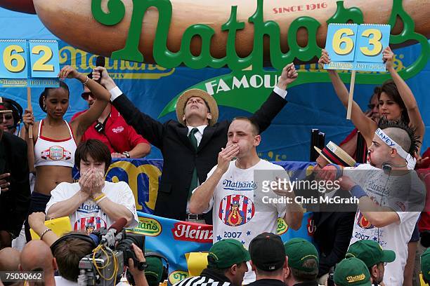 Takeru Kobayashi of Japan, Joey Chestnut of San Jose and Patrick Bertoletti of Chicago stuff hotdogs in their mouths in the closing minutes of the...