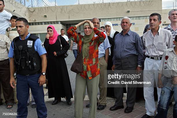 An Israeli prison guard and Palestinians, waiting outside the prison to visit relatives in Israeli detention, watch as a van with four Jordanian...