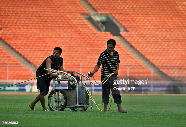 Jakarta, Java, INDONESIA: Workers spray water on grass at the Gelora Bung Karno stadium in preparation for the upcoming AFC Asian Cup 2007 tournament...