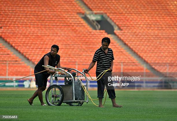 Jakarta, Java, INDONESIA: Workers spray water on grass at the Gelora Bung Karno stadium in preparation for the upcoming AFC Asian Cup 2007 tournament...